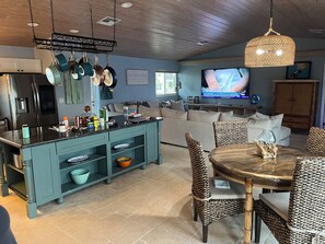 A modern kitchen with a central island, dining area with wicker chairs, and a television in the living room. - Water front 5-bedroom house with boat dock in beautiful Marathon (Marathon)
