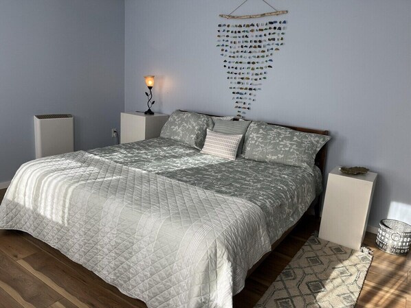 Un dormitorio con cama, mesitas de noche, una obra de arte en la pared y una lámpara de pie.