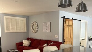 Una cocina moderna con una isla central, un sofá rojo e iluminación colgante.