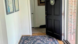 Ein Flur mit einer schwarzen Tür, einem gemusterten Teppich und zwei gerahmten Karten an der Wand.