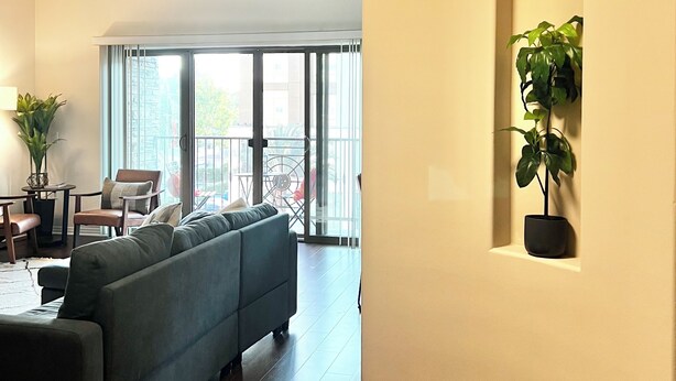 A modern living room with a curved ceiling, a large sofa, a dining area with a table and chairs, and a potted plant.