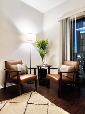A room with two leather chairs, a small table with a plant, a lamp, and a view of the outside through a window. - Cozy, Sunlit 2BR w/ Pool, Gated Parking, 10 min to LA, 2 Parking, Walk to Food (Monterey Park)