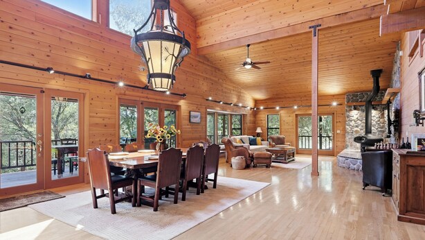 A spacious wooden cabin with a dining area, seating, and a fireplace.
