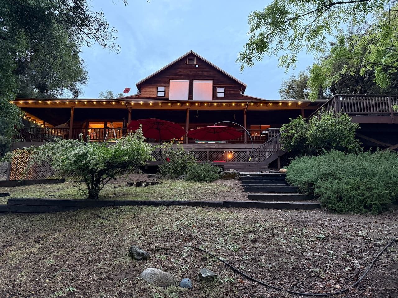 A wooden cabin with a covered porch, outdoor seating, and a staircase leading to a deck.