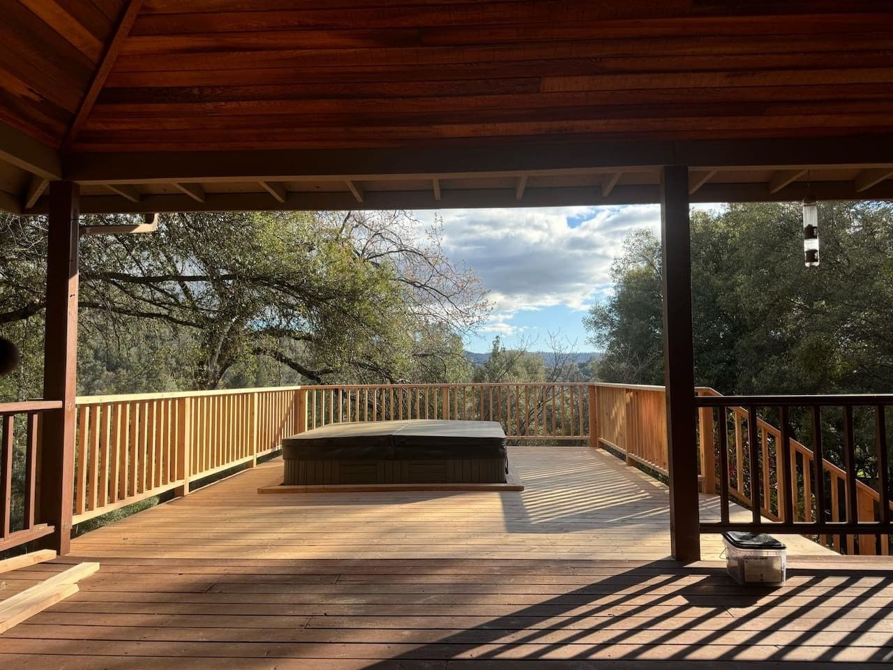 A wooden deck with a bench, surrounded by a wooden railing, overlooking a natural landscape.