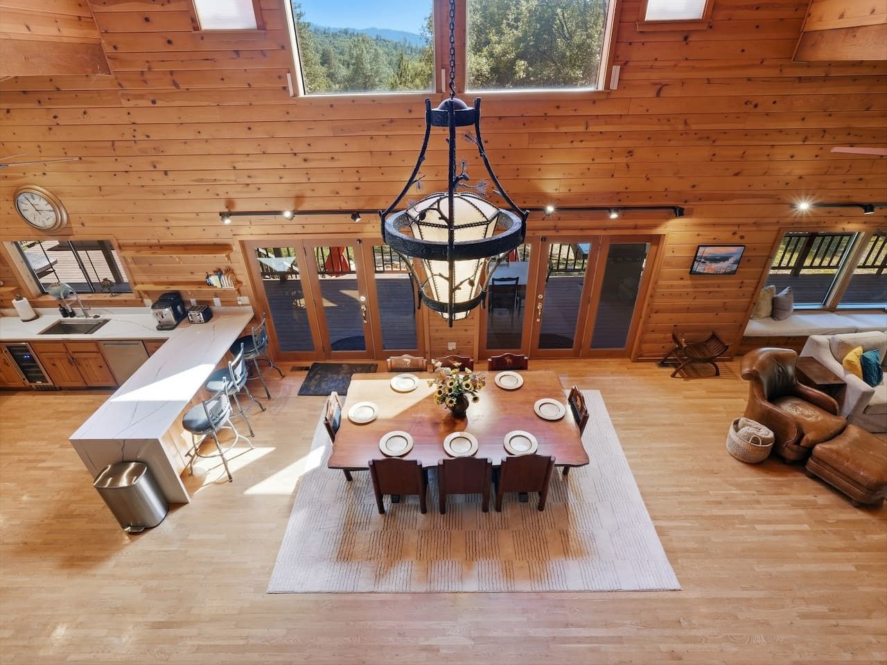 A spacious dining area with a wooden table and chairs, a hanging light fixture, and a view of the outdoors.
