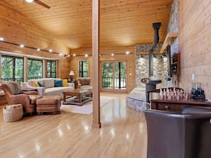 Un salon spacieux doté d’une cheminée, de parquets en bois et de grandes fenêtres.
