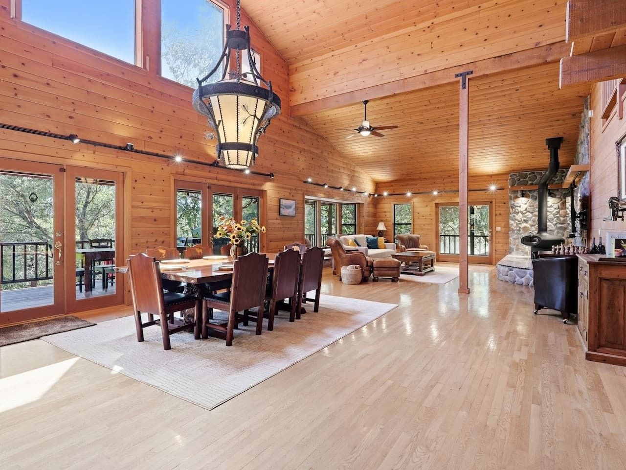 A spacious wooden interior with a dining area, a fireplace, and large windows.