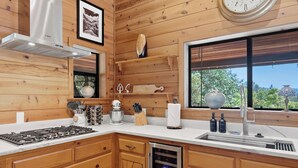 A kitchen with wooden walls, a Bosch range hood, a clock, and a window with a view.