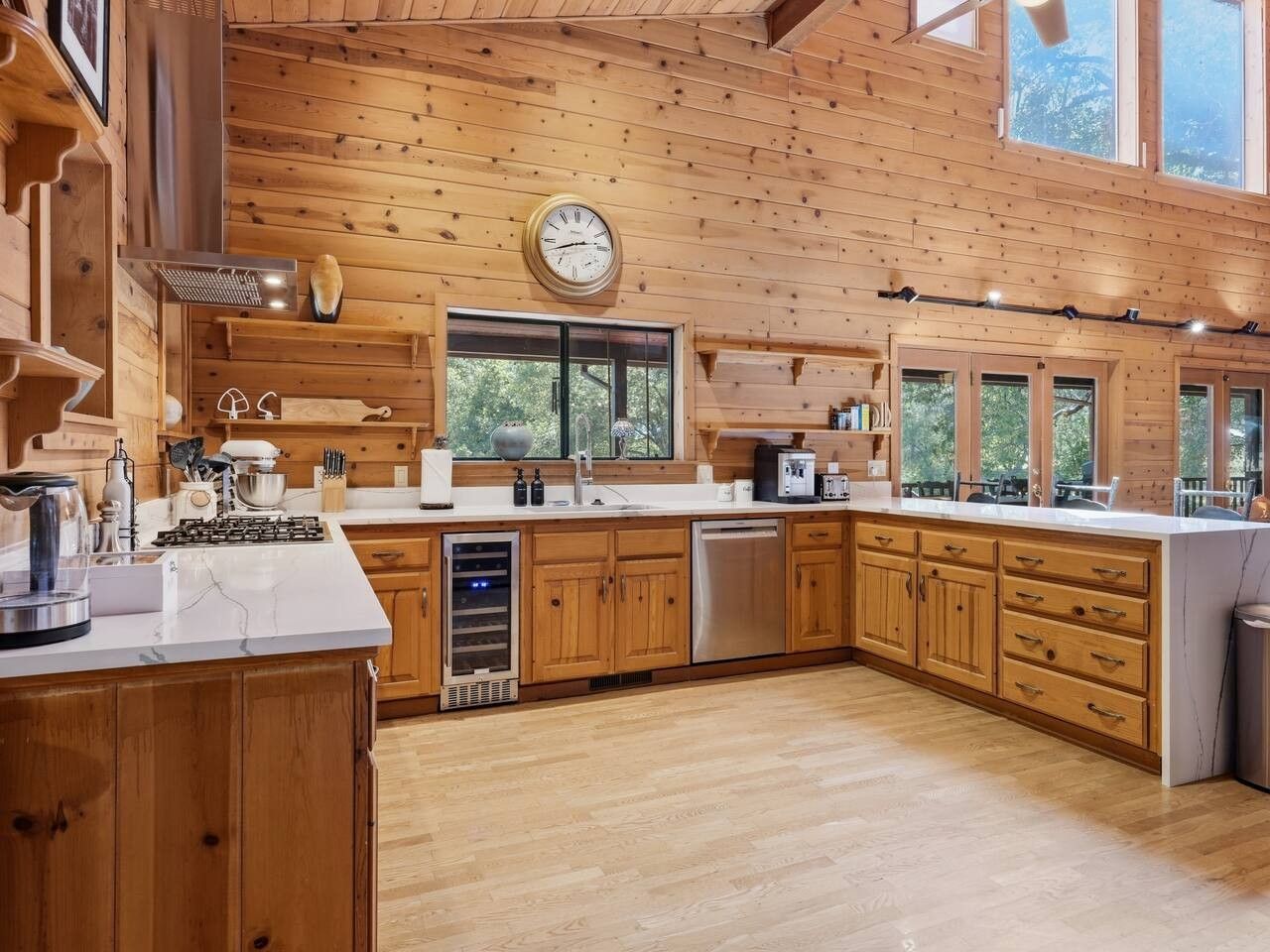 A spacious kitchen with wooden cabinets, a large island, and a clock on the wall.