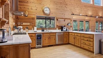 A spacious kitchen with wooden cabinets, a large island, and a clock on the wall.