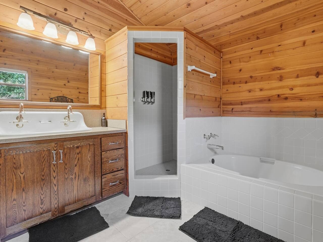 A wooden cabin bathroom with a wooden vanity, a shower, and a bathtub.