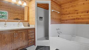 A wooden cabin bathroom with a wooden vanity, a shower, and a bathtub.