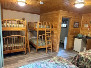 Une cabine avec des lits superposés, une petite kitchenette et une porte donnant sur une autre pièce.
