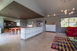Ein geräumiger Wohnbereich mit einer großen Kochinsel, einem roten Sofa und einem farbenfrohen Teppich.