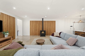 Una sala de estar moderna con un sofá, una pared decorativa de madera, un televisor y una chimenea.