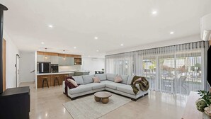 Ein modernes Wohnzimmer mit einer Eckcouch, einem Couchtisch und einer Küche im Hintergrund.