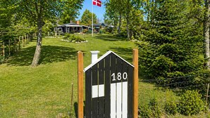 Una cabana de fusta amb un rètol amb el número 180, envoltada de vegetació i una bandera.