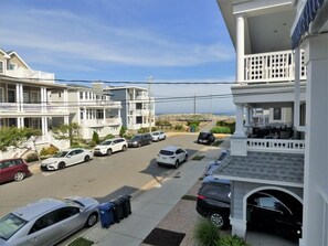 A residential street with multiple two-story houses, parked cars, and a clear sky. - Ocean View Beach Block Condo | 4BR | Private Elevator | Large Deck | Sleeps 10 (Ocean City)