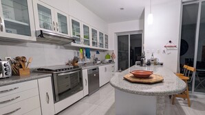 A modern kitchen with a central island, stainless steel appliances, and a dining area with a table and chairs. - Jardin Elvira (Cuernavaca)