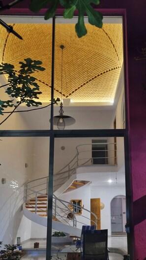 A modern interior with a staircase, a hanging light fixture, and a large window. - Jardin Elvira (Cuernavaca)