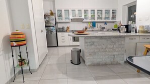 A modern kitchen with white cabinets, a granite countertop island, and a trash can. - Jardin Elvira (Cuernavaca)
