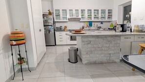 A modern kitchen with white cabinets, a granite countertop island, and a trash can. - Jardin Elvira (Cuernavaca)