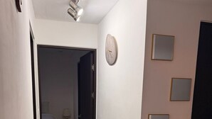 Ein Flur mit einem Bett, einem Nachttisch und einer Wanduhr.