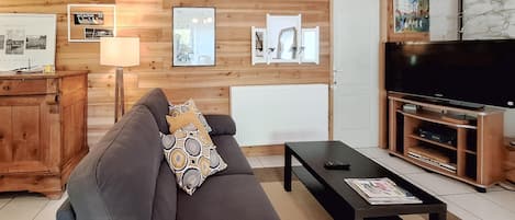 A living room with a sofa, a coffee table, a TV, and wooden panel walls.