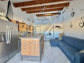 Eine moderne Küche mit Kochinsel, Holzschränken und einem Edelstahlkühlschrank.