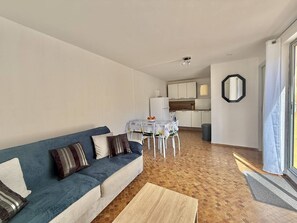 Ein Wohnzimmer mit einer Couch, einem Couchtisch und einer Küche im Hintergrund.