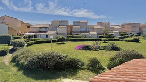 Un barrio residencial con casas adosadas, cielo despejado y un avión a lo lejos.