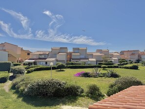 Un barrio residencial con casas adosadas, cielo despejado y un avión a lo lejos.