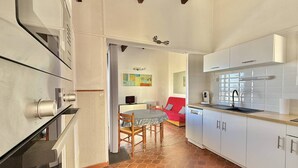 Una cocina moderna con armarios blancos, un comedor con sofá rojo y piso de baldosas.