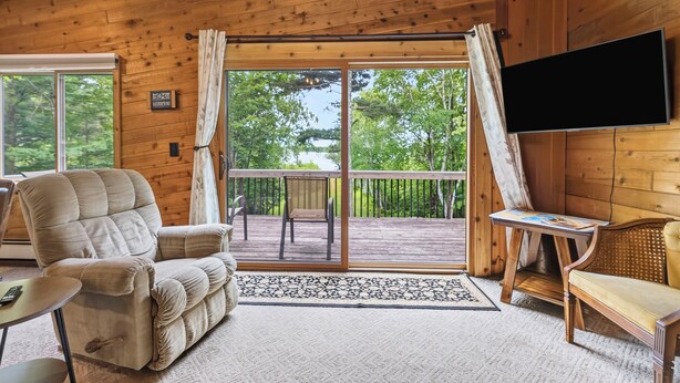 A wooden cabin with a sofa, a table, and a TV mounted on the wall. - Discover Taylor Creek Lodge on Lake Namakagon (Cable)