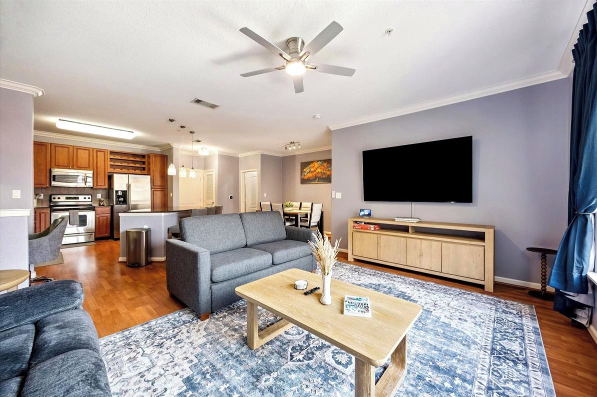 A modern living room with a grey sofa, wooden coffee table, and a flat-screen TV.