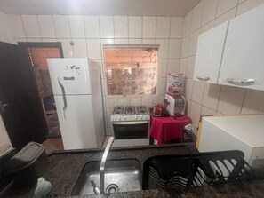 Cozinha compacta com geladeira, fogão, pia e bebedouro.
