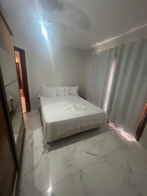 Una habitación de hotel con una cama, un espejo, una cortina y una lámpara.