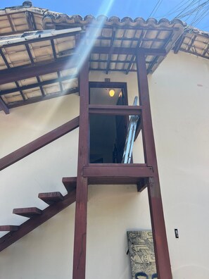 A wooden staircase leading to a room with a tiled roof and a window. - Residencial Ouro Preto  (Porto Seguro)
