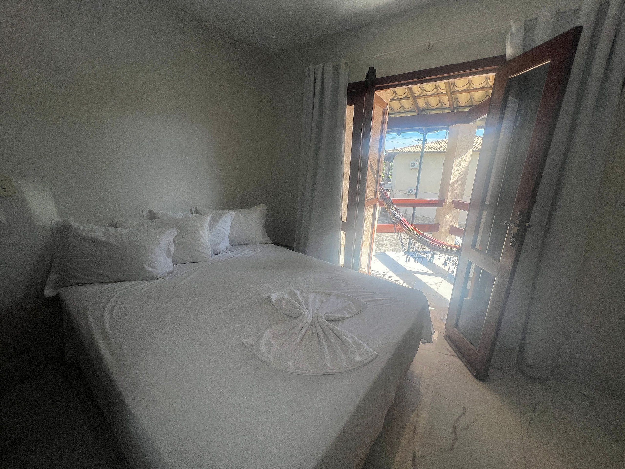 Habitación de hotel con cama, almohadas y vistas por una puerta abierta.