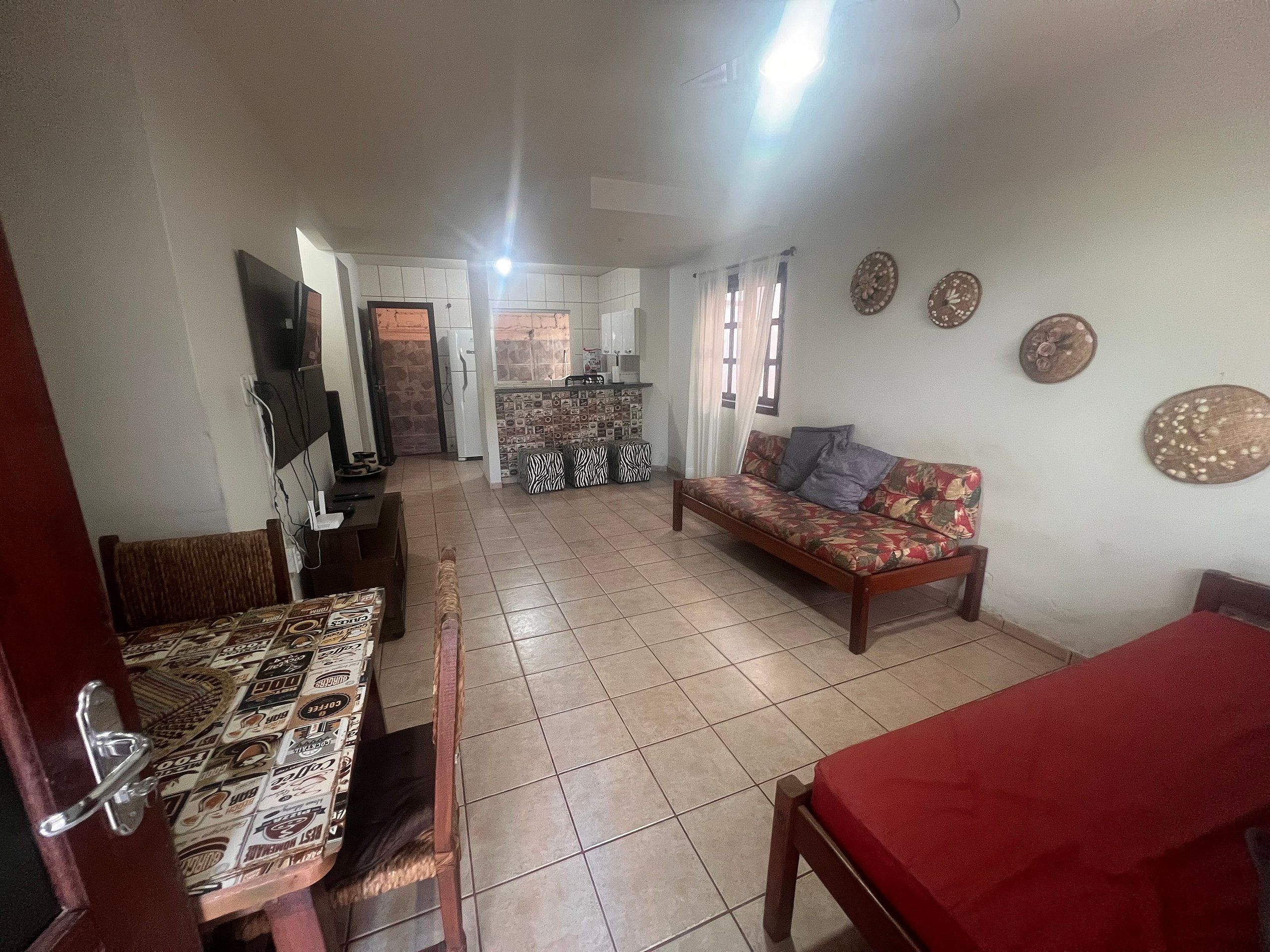 A living room with a sofa, a dining table, and a kitchen in the background.