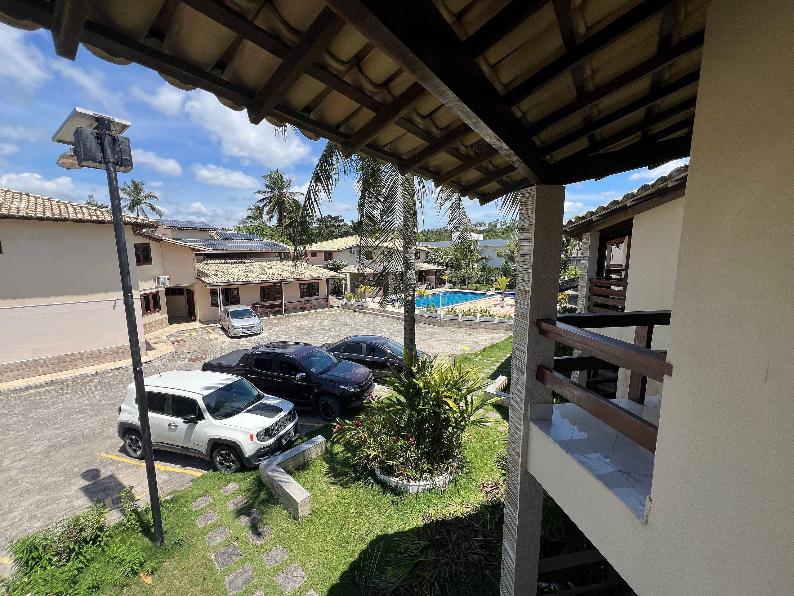 A residential area with a covered porch, a swimming pool, and parked cars.