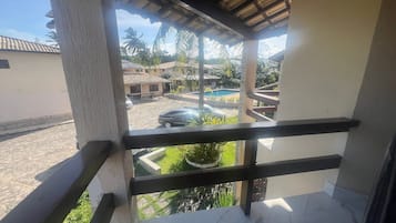 A balcony with a view of a swimming pool, palm trees, and residential buildings.