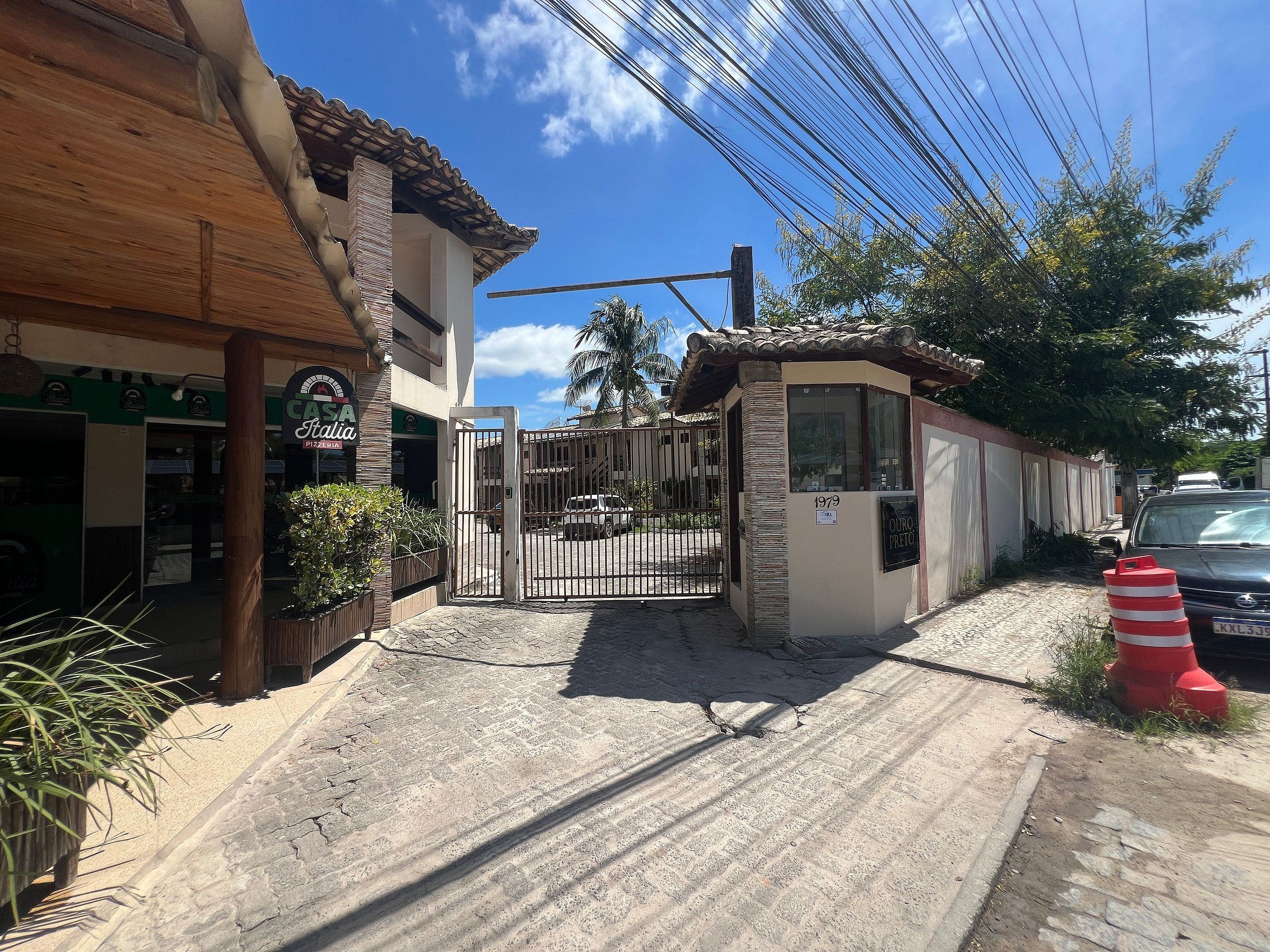 A gated entrance with a building featuring a tiled roof and a sign that reads 'Casa Filia Pizzeria.'