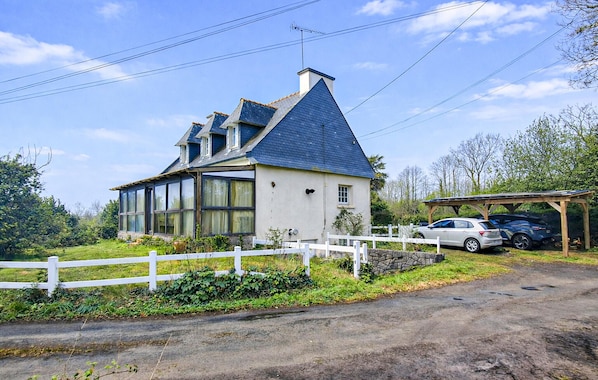 A house with a large window, a garage, and a white fence.