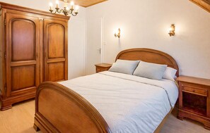 A bedroom with a wooden bed, nightstands, a wardrobe, and wall sconces.