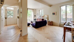 A spacious living area with a herringbone floor, a dining table, and a sofa. - La Maison Raspail - Welkeys (Bois-Colombes)