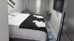A hotel room with two beds, a flat-screen TV, a refrigerator, and a window with curtains. - ORA BEACH RESIDENCE  (Ipojuca)