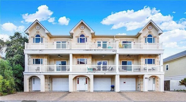 A multi-story residential building with a symmetrical facade, multiple balconies, and a central entrance. - Steps from the sand. Miles from stress. (Tybee Island)