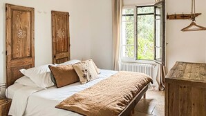 Ein Schlafzimmer mit einem Bett, einem Holzschrank, einem Fenster mit Vorhängen und einem Kleiderhaken.